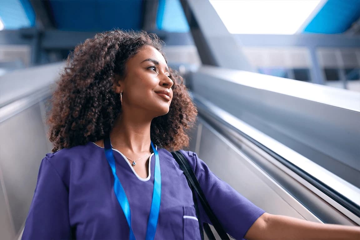 Female nurse in purple scrubs looking off into distance. 