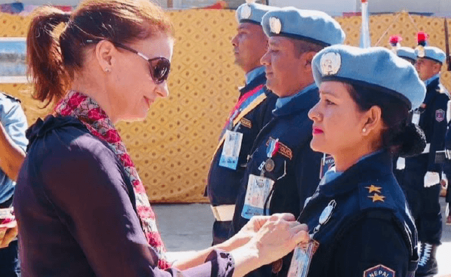 A woman pinning a pin on a woman in a military uniform.
